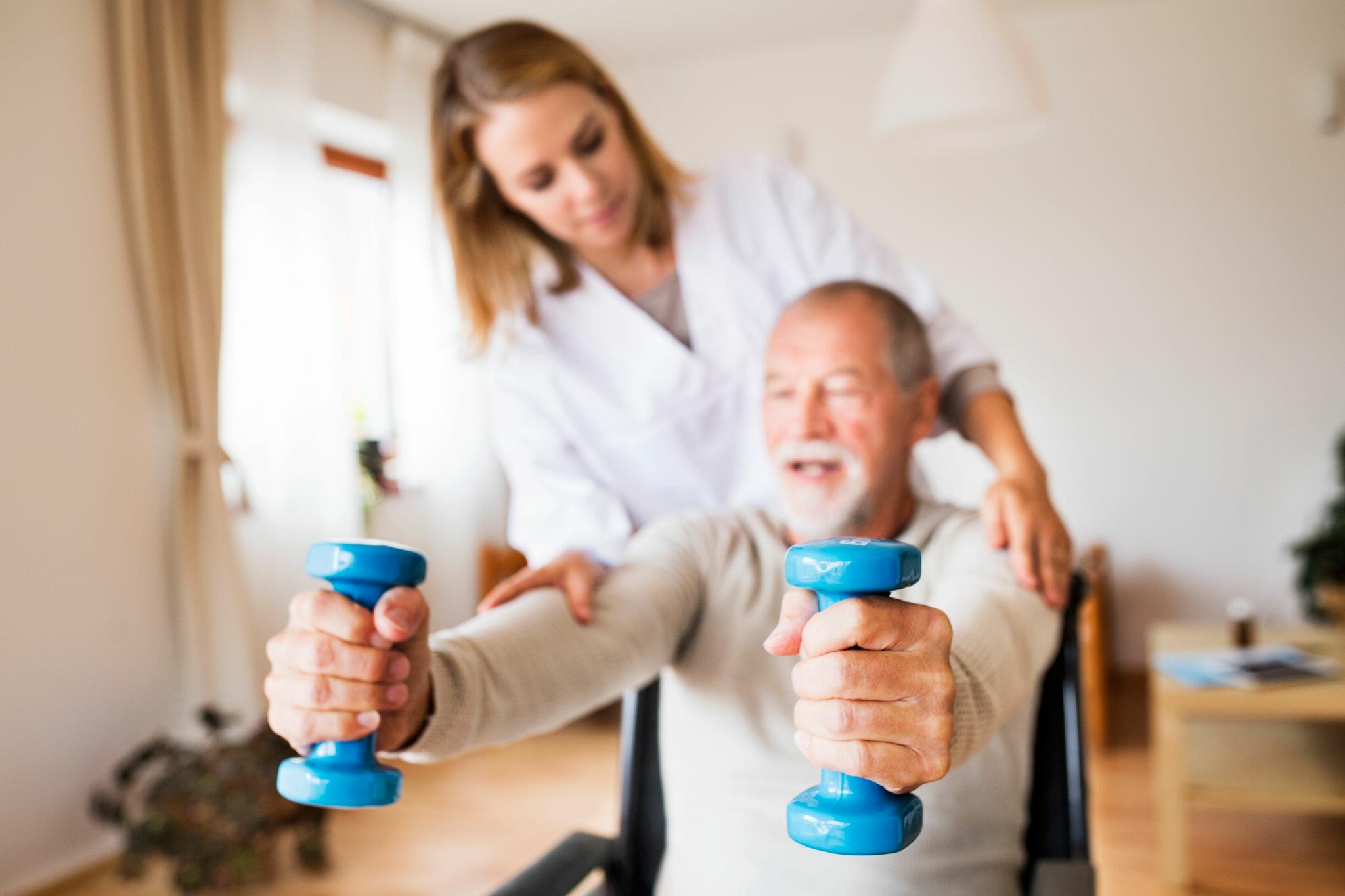 Nurse and Senior Man in Wheelchair doing Home Exercising