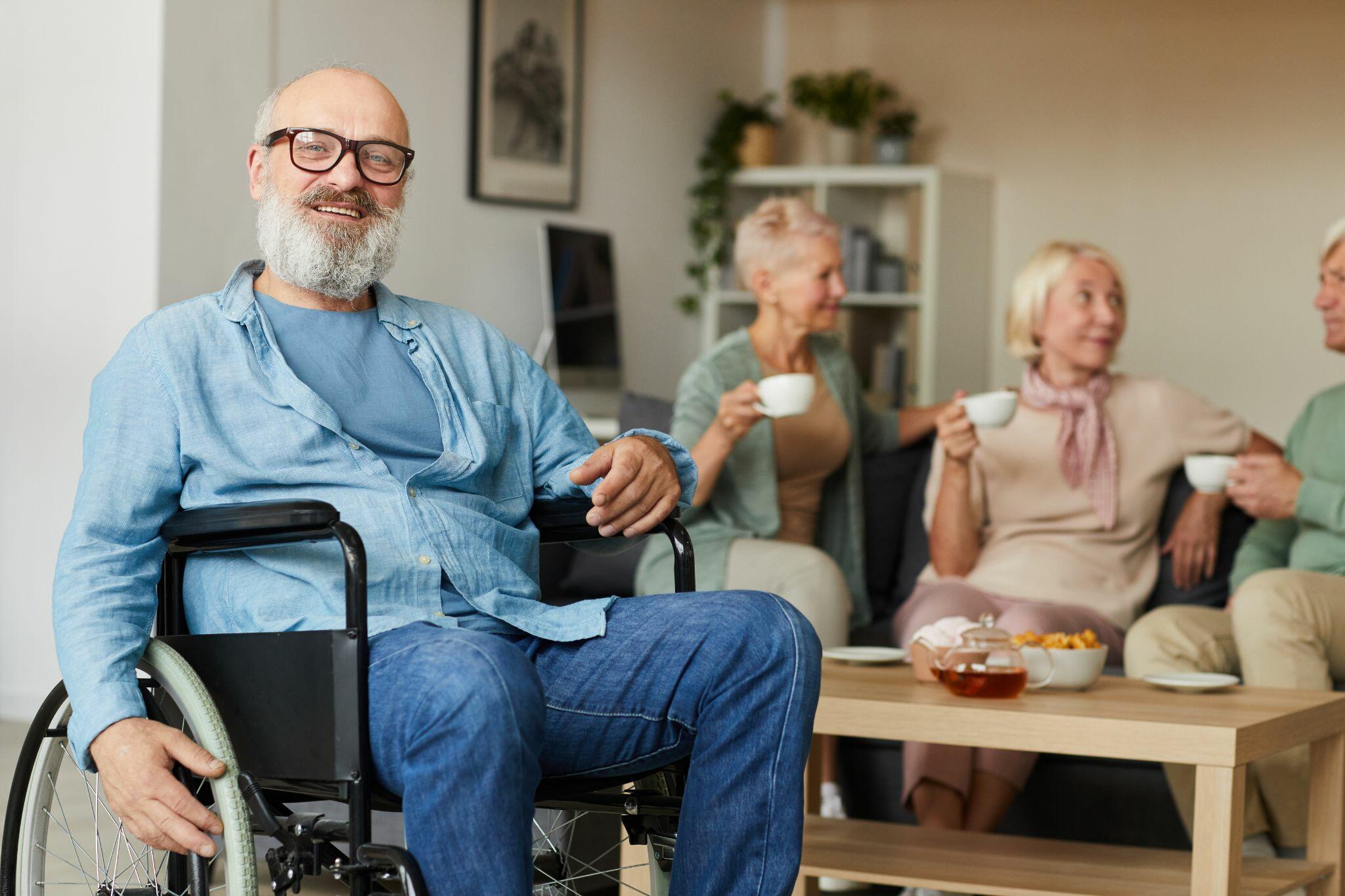 Senior Man Sitting in Wheelchair with Family Behind him