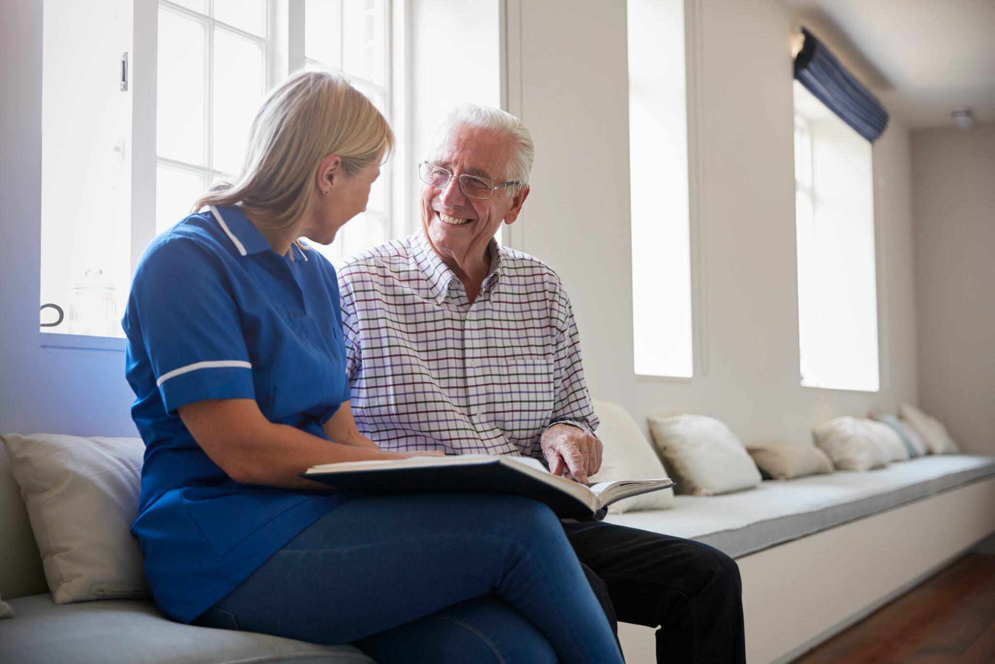 Senior Man Looking at Photo Album with Nurse