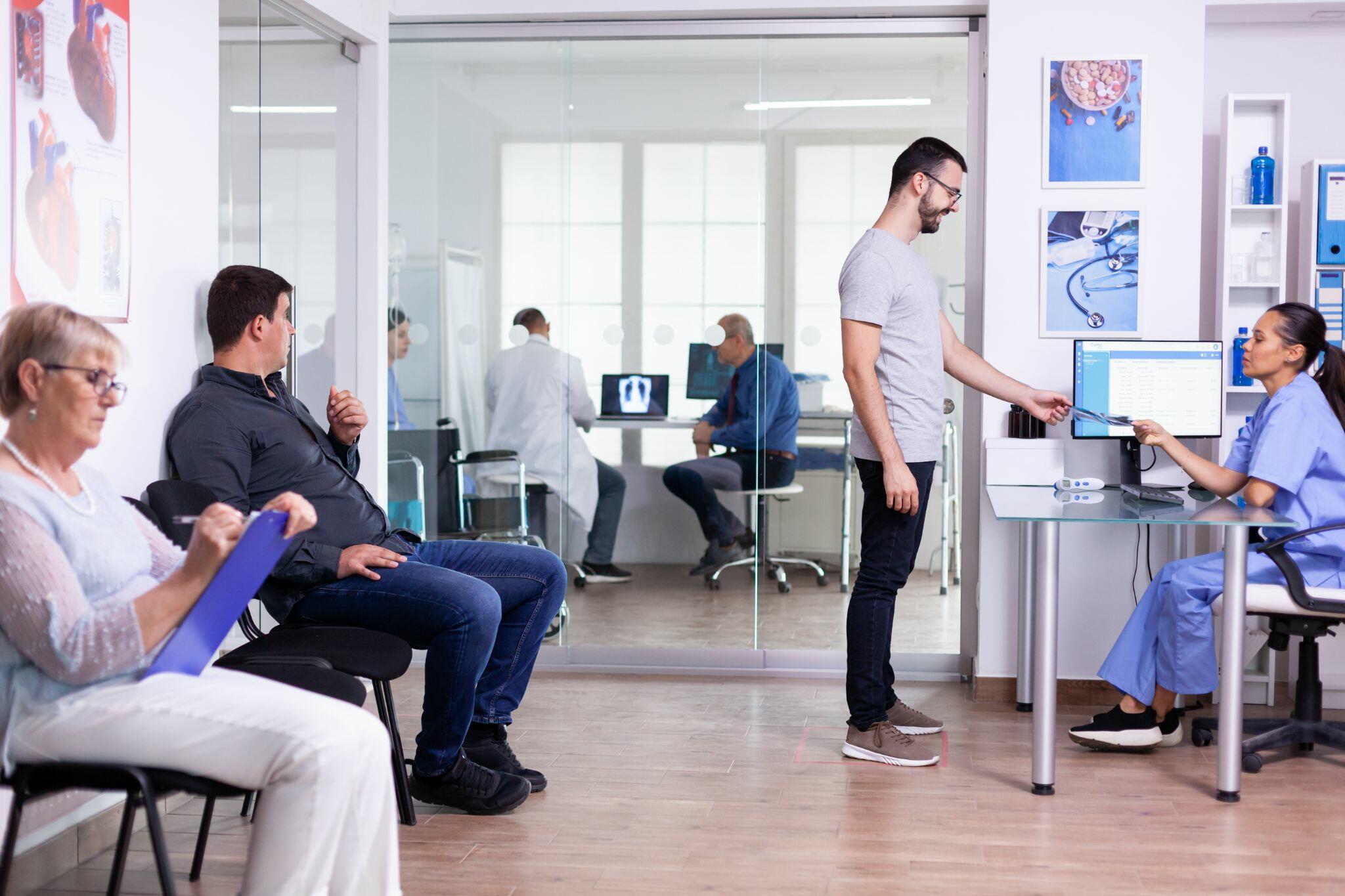 Young Man Talking with Nurse in Hospital Reception